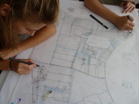 Mains qui dessinent au feutre sur un grand plan du site