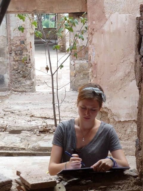 Une participante dessine assise dans les ruines de l’usine