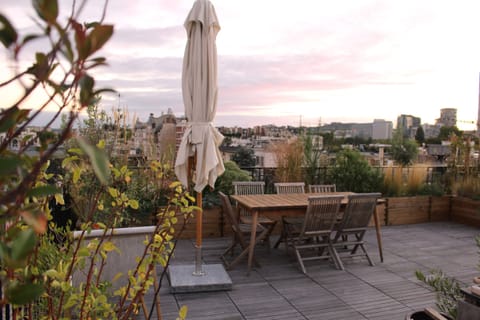 Terrasse en bois avec table et parasol, entourée de plantations