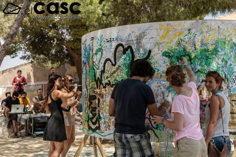 Participants painting together on a large ring under the pines