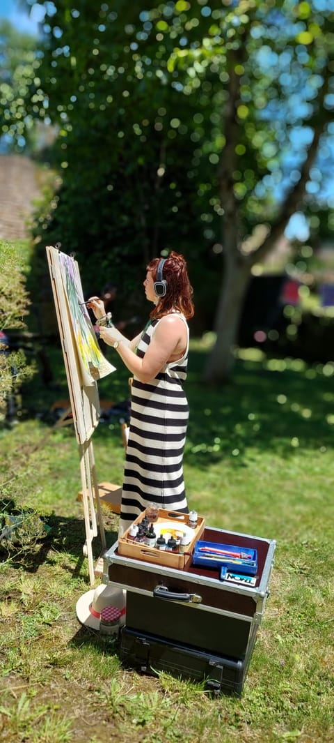 Alice Stevens painting at an easel, standing on the grass