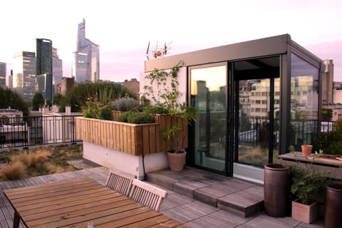Terrasse plantée sur un toit au coucher du soleil, tours au loin