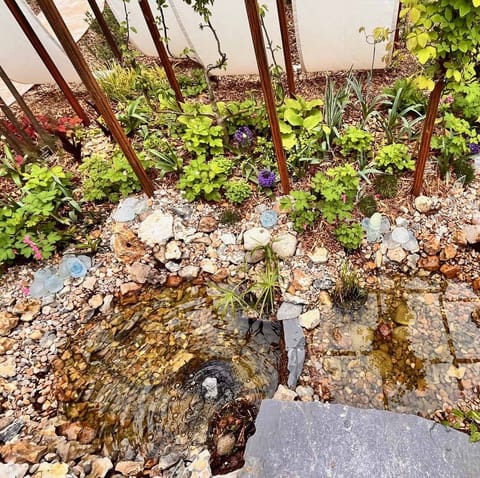 Gros plan sur des roches, des galets de verre et de jeunes plantes au pied de poteaux rouillés