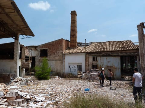 Intérieur de l’usine en ruine : toiture effondrée, charpente métallique et gravats