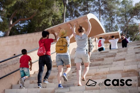 Young people carry a large curved panel up a flight of steps
