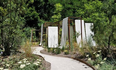 Allée de sable bordée de plantes, menant à la structure de panneaux blancs